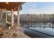 Outdoor seating area with stone flooring, columns, and a view of the lake at 102 Anna Lake Ln, Cary, NC 27513