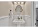 Small powder room with wainscoting, a pedestal sink, round mirror, and bronze fixtures at 106 Ferris Wheel Ct, Cary, NC 27513