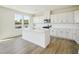 Bright kitchen features a center island, white cabinets, stainless appliances and wood-look flooring at 106 Willow Cameron Way, Angier, NC 27501