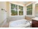 Soaking tub featuring tile surround and a view of the landscaped backyard at 116 Wright Hill Dr, Durham, NC 27712