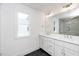 Bright bathroom with dual sink vanity, large mirror, black tile and white cabinets at 1211 Chaney Rd, Raleigh, NC 27606