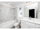 Bathroom features a shower and tub combination with marble tile surround and white vanity at 1211 Chaney Rd, Raleigh, NC 27606