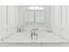 Close-up of a bathtub with white marble surround and shuttered window view at 1416 Barony Lake Way, Raleigh, NC 27614