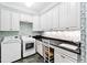 Bright laundry room featuring front-loading washer/dryer, cabinetry and black countertop at 1416 Barony Lake Way, Raleigh, NC 27614