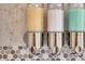 Close-up of shampoo, conditioner, and soap dispensers in the bathroom against a gray mosaic tiled wall at 171 Springberry Ln, Chapel Hill, NC 27517