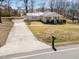 Single-story home with long driveway featuring a metal roof, front porch, and lawn at 231 Patterson Dr, Roxboro, NC 27573