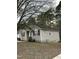 Single-story home shows a side angle with neutral siding and black shutters, set on a partially shaded lot with mature trees at 309 Gladstone Dr, Durham, NC 27703