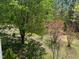 Backyard with lush landscaping and trees on a sunny day at 328 Cone Dr, Henderson, NC 27537