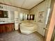 Bathroom featuring a corner tub, vanity with sink, unique mirror, and floral wallpaper at 328 Cone Dr, Henderson, NC 27537