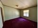 Bedroom with purple carpet, a window, and neutral-colored walls creating a comfortable space at 328 Cone Dr, Henderson, NC 27537