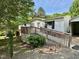 Inviting white home featuring a wooden ramp and deck surrounded by lush greenery at 328 Cone Dr, Henderson, NC 27537