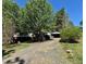View of the house from the driveway with mature trees and shrubbery at 328 Cone Dr, Henderson, NC 27537