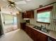 Kitchen featuring wood cabinets, a double sink, and wallpaper, connecting to another room at 328 Cone Dr, Henderson, NC 27537