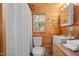 Compact bathroom with wood paneling, a toilet, a sink, and a shower with a white curtain at 409 S 13Th St, Lillington, NC 27546