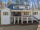 Rear exterior of a two-story home with white siding, black trim, and an outdoor living space at 4501 Bartlett Dr, Raleigh, NC 27609