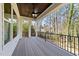 A serene covered deck with a ceiling fan and black metal railings, providing views of the surrounding trees at 4501 Bartlett Dr, Raleigh, NC 27609