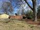 Grassy backyard with yellow outbuilding, wooden fence, mature trees, and landscaping at 531 N Main St, Graham, NC 27253