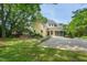Well-manicured yellow home with mature trees, landscaping, and large driveway at 531 N Main St, Graham, NC 27253