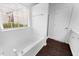 Bathroom with white tub and shower with dark wood floors at 6013 Shelane Ct, Raleigh, NC 27610