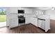 Bright kitchen with white cabinets, stainless steel appliances, and dark wood-look flooring at 6013 Shelane Ct, Raleigh, NC 27610