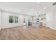 Open-concept living space with kitchen island and wood-look floors, bathed in natural light from large windows at 624 Brittany Ct, Durham, NC 27703