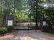 Wanderwood community entrance with a secure black gate and brick pillars, nestled among lush greenery at 6709 Windchase Dr, Rocky Mount, NC 27803