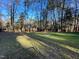 Backyard featuring lush lawn, mature trees, landscaping, and a fire pit at 7780 Brookdale Dr, Raleigh, NC 27616