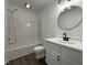 Well-lit bathroom with a shower-tub combo, modern vanity, matte black hardware and round mirror at 7780 Brookdale Dr, Raleigh, NC 27616