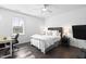 Well-lit bedroom featuring hardwood floors, ceiling fan, a cozy bed, desk and TV, offering comfort and function at 8401 Zinc Autumn Path Path, Raleigh, NC 27615