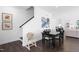 Bright dining area featuring dark wood floors, black table set, and modern artwork leading to stairway at 8401 Zinc Autumn Path Path, Raleigh, NC 27615