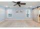 Inviting bedroom featuring a sliding barn door, plush carpeting, ceiling fan, and large windows at 10115 Mizner Ln, Raleigh, NC 27617