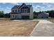 View of the home featuring a two-car garage and a concrete driveway with a neighboring home being built nearby at 108 Grove Township Way, Angier, NC 27501