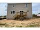 Tan two-story home back exterior with a wooden deck and stairwell on a sand lot at 119 Grove Township Way, Angier, NC 27501