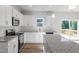 Well-lit kitchen features stainless appliances, white cabinets, granite countertops, and access to deck at 119 Grove Township Way, Angier, NC 27501