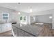 Open concept kitchen with granite island, white cabinetry, stainless appliances, and easy access to the living area at 119 Grove Township Way, Angier, NC 27501