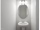 Compact powder room with pedestal sink, oval mirror, and modern lighting at 119 Grove Township Way, Angier, NC 27501
