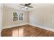 Cozy bedroom with wood floors, paneled walls, a ceiling fan, and a large window at 210 S General Lee Ave, Dunn, NC 28334