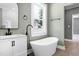 Bright bathroom featuring a stand alone tub, vanity, and views to a closet and window at 221 Charlotte Ave, Sanford, NC 27330