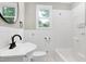 Bright bathroom features a pedestal sink, toilet, and tiled shower/tub with window for natural light at 221 Charlotte Ave, Sanford, NC 27330