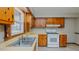 Traditional kitchen featuring wood cabinets, white appliances, a double-basin sink, and natural light at 2720 Amherst Ave, Burlington, NC 27215