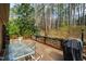 Back deck with outdoor table set and grill surrounded by a green wooded landscape at 5008 Hermitage Dr, Raleigh, NC 27612