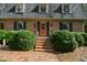 Close up of a brick home exterior featuring a pastel door and manicured shrubbery at 5008 Hermitage Dr, Raleigh, NC 27612
