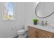 Bright bathroom featuring a modern vanity with a round mirror and window at 505 Colleton Rd, Raleigh, NC 27610