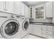 Well-equipped laundry room featuring a modern washer and dryer, storage cabinets, and a sink with lots of natural light at 5808 Valley Mist Ct, Raleigh, NC 27613