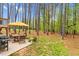A spacious backyard with a patio, dining set, and a wooded area featuring a playset and swing at 749 Bowden Rd, Chapel Hill, NC 27516