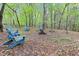 Relaxing outdoor fire pit area with blue Adirondack chairs amidst a wooded setting at 749 Bowden Rd, Chapel Hill, NC 27516