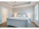 Bright main bedroom showcasing a tray ceiling, a large bed, bedside tables, and neutral-colored walls at 749 Bowden Rd, Chapel Hill, NC 27516