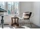 Cozy sitting area with a metal-framed chair, small round table, and large window offering views of a wooded area at 749 Bowden Rd, Chapel Hill, NC 27516