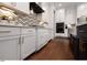 Modern kitchen featuring white cabinets, gold hardware, herringbone backsplash, and sleek black appliances at , Efland, NC 27243