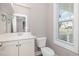 Clean bathroom with a white vanity, sleek mirror, and natural light from a nearby window at 104 Coats Ridge Dr, Benson, NC 27504